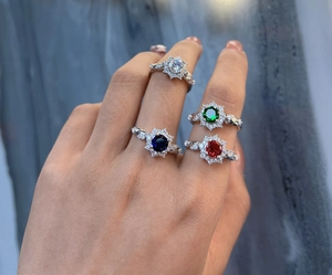Detail of four-claw silver rings featuring multi-color gemstones in a halo floral design
