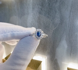 Macro detail of oval blue sapphire ring with double diamond halo on silver band