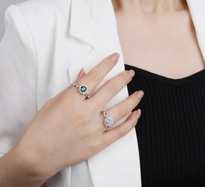 Close-up of four-prong silver rings with sparkling green and white circular gemstones