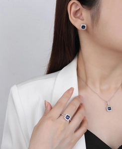 Detail of square blue gemstone jewelry set worn by a model in a white blazer