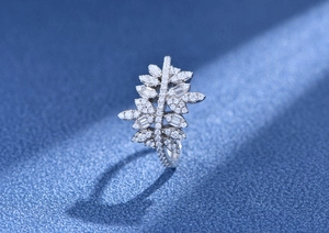 Vue macro d'une bague en argent en forme de feuille sertie de zircons sur fond bleu foncé