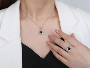 Detail view of silver necklace and ring set with square blue gemstones on a model