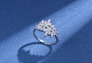 Macro d'une bague feuille en argent avec zircons sur fond bleu foncé texturé