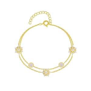 Zweilagiges goldenes Schneeflocken-Armband mit funkelnden Zirkonia auf weißem Hintergrund
