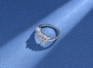 Détail macro d'une bague couronne en feuille avec micro-pavage de zircone sur fond bleu