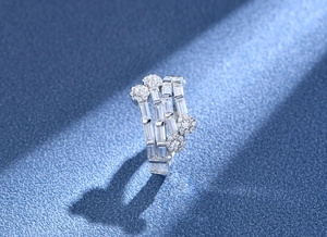 Macro shot of silver multi-layer ring with baguette and round zircon stones on blue texture
