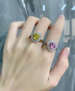 Detail of pink and yellow heart cut rings with halo diamond setting on hand