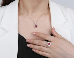 Elegant model wearing silver halo set with square red gemstone necklace and ring jewelry