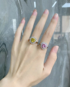 Close-up of heart-shaped halo rings with yellow and pink stones on a hand
