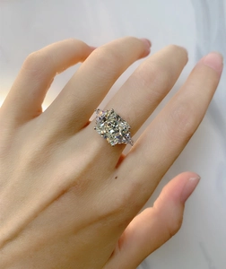 Close-up of a three-stone ring with cushion cut center stone on a person's hand