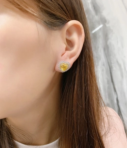 Detailed close-up of a heart-shaped yellow diamond earring worn by a model