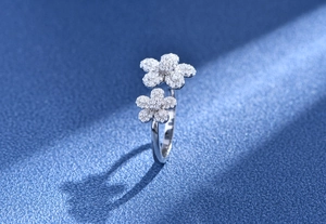 Macro detail of silver floral open ring with shimmering pavé set petals on dark background