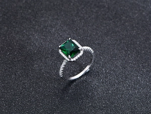 Vista macro di un anello in argento 925 con gemma verde rettangolare e contorno di zirconi