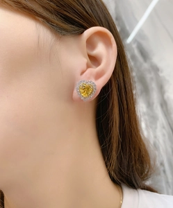 Macro shot of yellow heart-cut gemstone stud earrings with double halo diamond setting