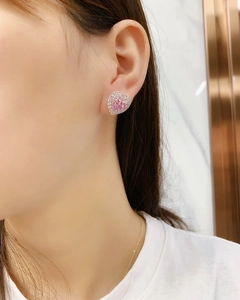 Close-up of pink heart-shaped crystal stud earring worn on a female earlobe