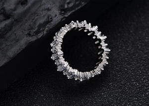 Macro shot of S925 sterling silver baguette cut eternity ring on black volcanic stone