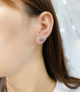 Detail of pink heart cut earring with double halo pavé setting worn on ear