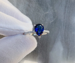 Macro detail of a pear-shaped blue sapphire ring with S925 silver pave setting