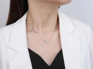 Close-up of S925 sterling silver butterfly necklace worn by model on a white blazer