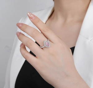 Gros plan d'une bague marquise avec diamant rose et double halo sur la main