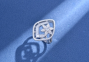 Detail shot of a silver floral ring with pave-set zircons on a dark blue background