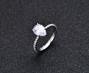 Macro shot of S925 sterling silver ring showing pear-cut sapphire and pave-set diamonds