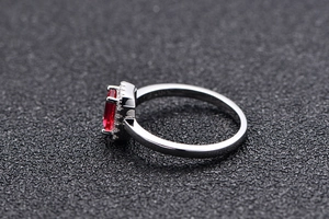 Detailed side view of silver ring showing oval red gemstone and secure claw setting
