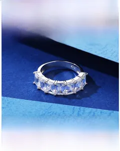 Détail des pierres de zircon taille émeraude et de l'anneau en argent 925 sur fond bleu