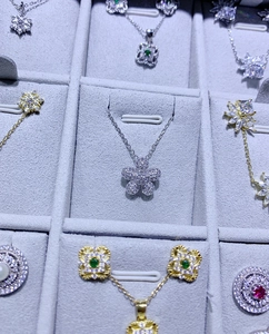 Détail de pendentifs en argent S925 avec fleurs serties de zircons et motifs de trèfles