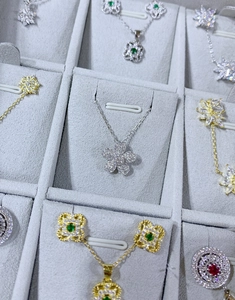 Vue détaillée de pendentifs fleurs et trèfles sertis de gemmes sur plateau en velours