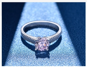 Macro shot of a round cut pink gemstone ring with zircon accents on silver band