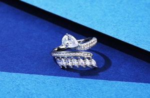 Macro detail of silver bypass ring featuring pear and marquise cut diamonds on blue background