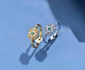Dettaglio macro di anelli in argento e oro con pietre verdi e accenti di diamanti