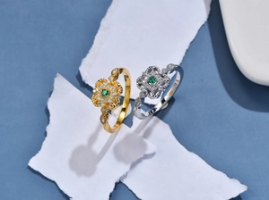 Dettaglio macro di anelli d'argento vintage con gemma verde e design a quadrifoglio traforato