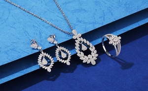 Macro detail of leaf-shaped silver jewelry set with micro-pave crystals on blue background