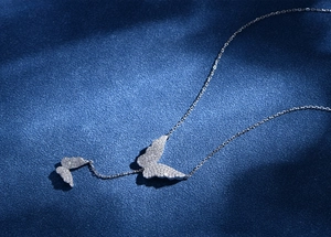 Macro detail of silver S925 butterfly pendant with pave stones on blue velvet