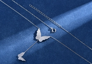 Macro shot of silver S925 necklace featuring pavé butterfly pendants and tassel detail