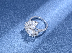 Détail d'une bague tourbillon en argent S925 sertie de zircons sur fond bleu texturé