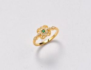 Dettaglio dell'anello in argento 925 con gemma verde e filigrana floreale dorata lucida