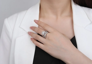 Macro shot of silver ring with crossover bands and emerald cut stone on a model