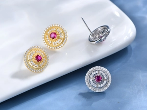 Detailed macro view of gold and silver circular earrings with red gemstones and crystals