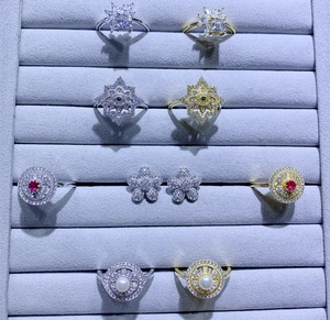 Détail macro de boucles d'oreilles fleurs serties et de bagues en zircon dans un plateau