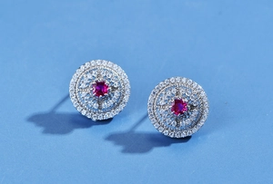 Macro shot of circular镂空earrings with red gemstones and pavé diamonds in silver
