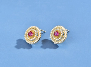Detail of round gold-plated earrings with red gemstone and white zircon pavé setting