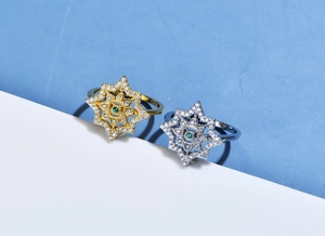 Close-up of gold and silver eight-pointed star open rings with green gemstone core