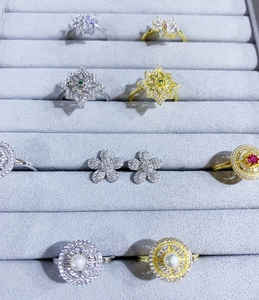 Gros plan de boucles d'oreilles fleurs et bagues en cristal dans un plateau en velours gris