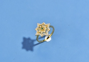 Detailed top view of a gold starburst ring featuring emerald and zircon pavé settings