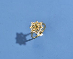 Macro detail of gold-plated octagram ring featuring pavé zircons and green center stone