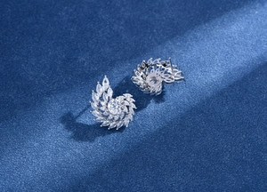 Vue macro des boucles d'oreilles tourbillonnantes en argent avec zircons sur velours bleu