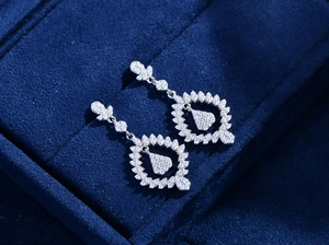 Macro shot of 925 sterling silver leaf earrings with zircon pendants on blue velvet